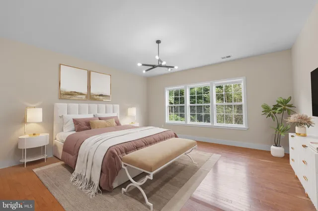 a spacious bedroom with a bed a chandelier and a window