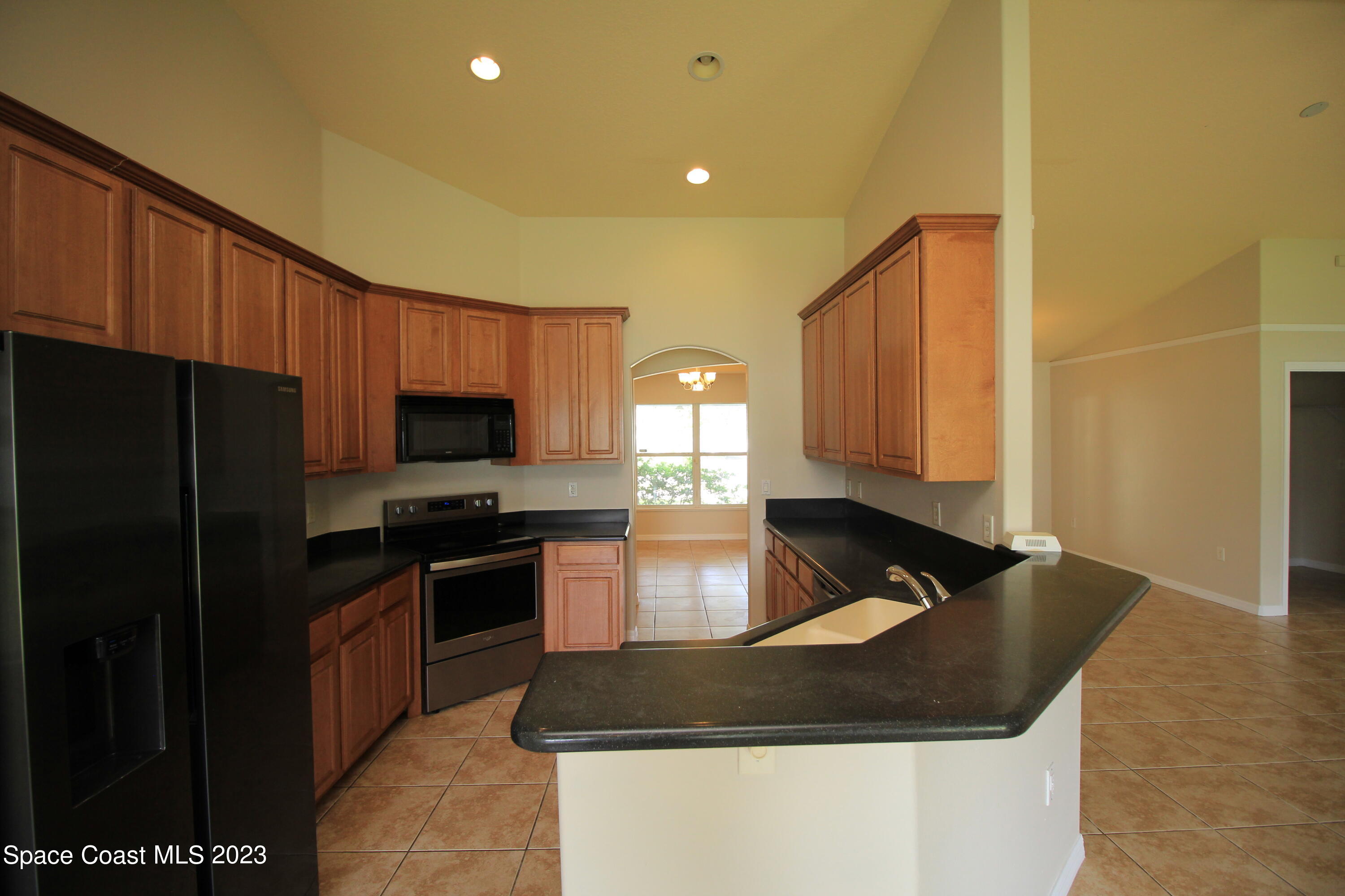 492 Eldron Boulevard Southeast Palm Bay, FL 32907 - Photo 14 of 28 a kitchen with granite countertop wooden cabinets a refrigerator and a sink