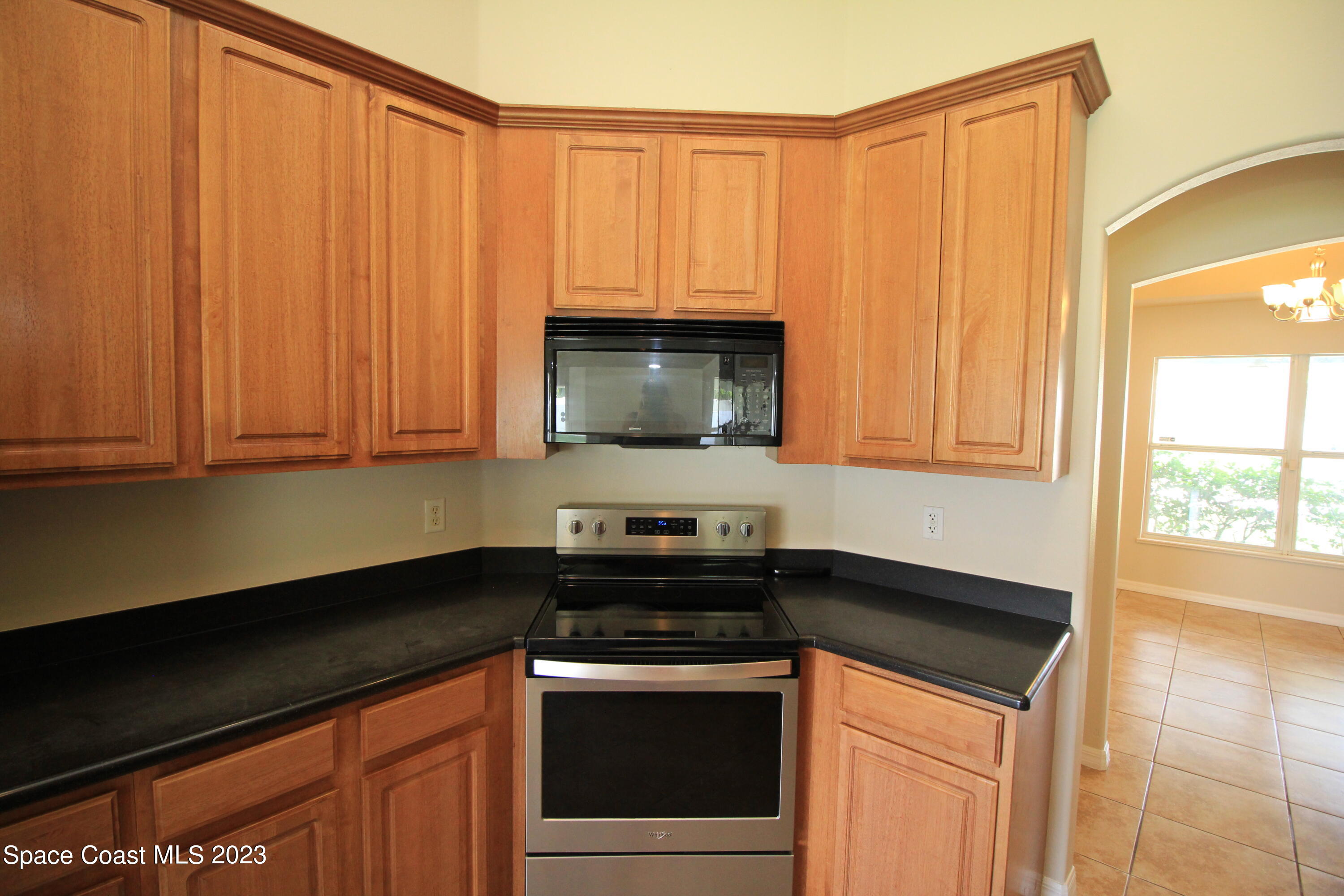 492 Eldron Boulevard Southeast Palm Bay, FL 32907 - Photo 16 of 28 a kitchen with granite countertop white cabinets and black appliances