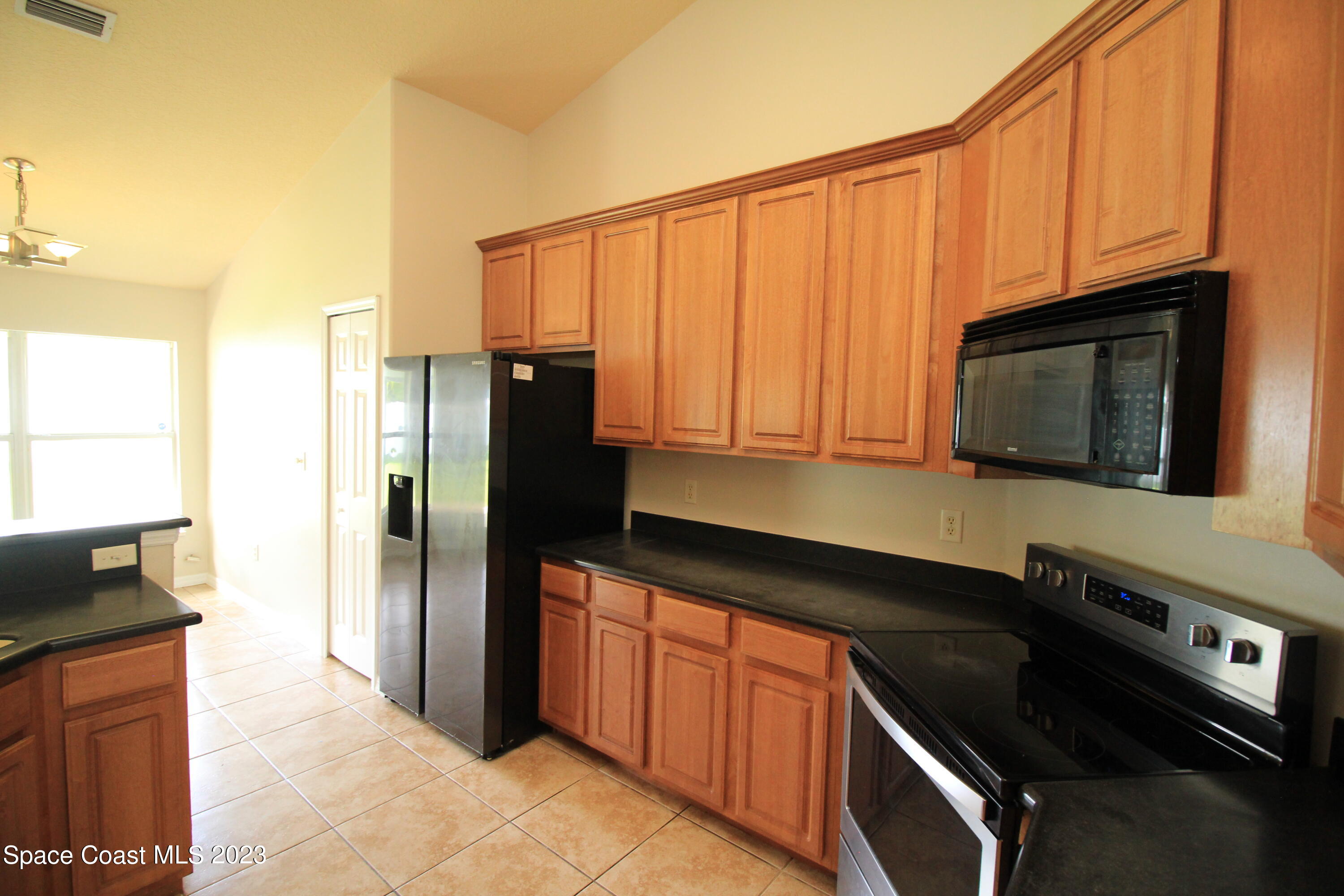 492 Eldron Boulevard Southeast Palm Bay, FL 32907 - Photo 17 of 28 a kitchen with stainless steel appliances granite countertop a refrigerator stove and microwave