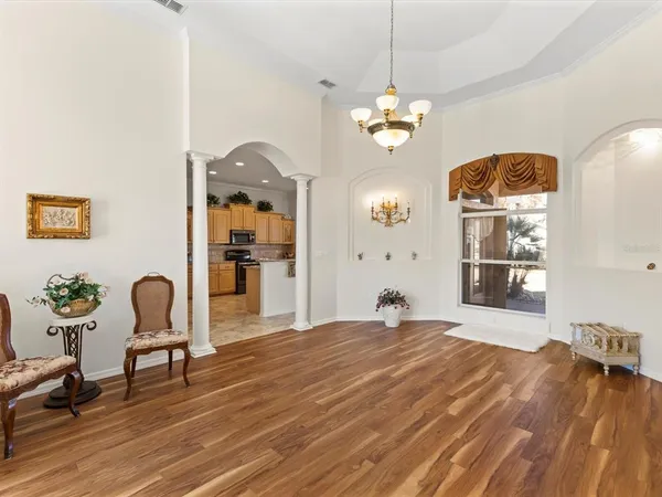 a view of a room with wooden floor chandelier and windows