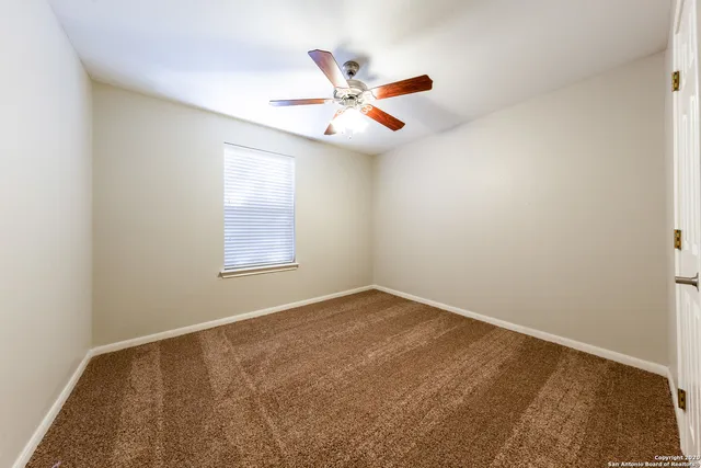 an empty room with window and ceiling fan