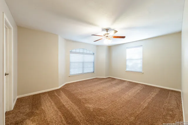 an empty room with windows and ceiling fan
