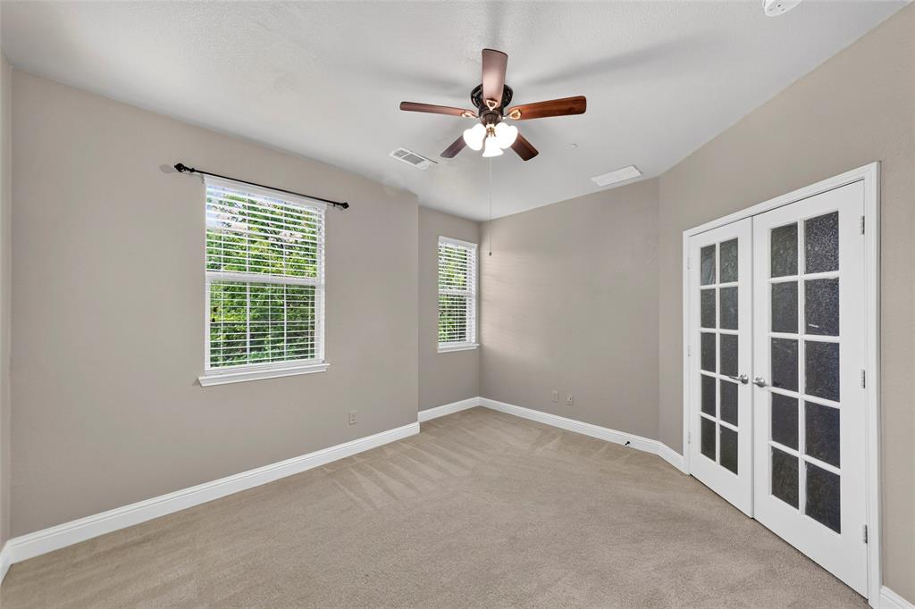 8607 Calvin Road Irving, TX 75063 - Photo 25 of 39 Bedroom featuring neutral carpeting, light gray walls, a ceiling fan with integrated lighting, two windows with white blinds, and white French doors with frosted glass panels