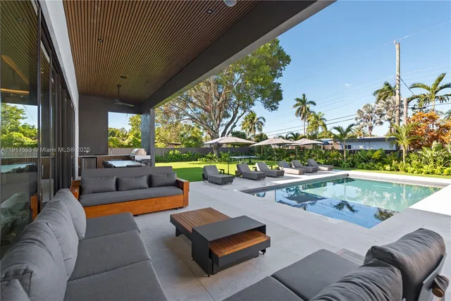 a view of a patio with couches table and chairs with wooden floor and fence