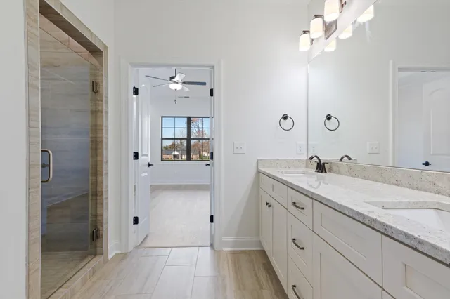 a spacious bathroom with a granite countertop sink a mirror and shower