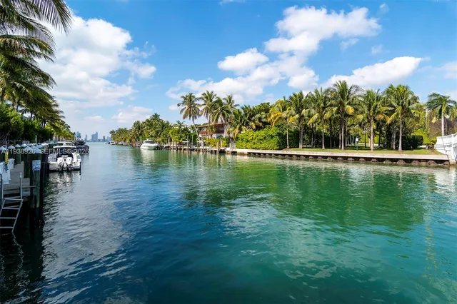 a view of an empty room with wooden floor and a kitchen