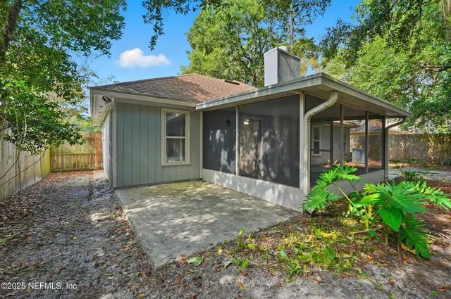 a view of a house with small yard plants and a large tree
