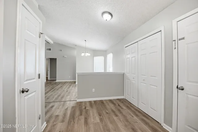 a view of a hallway with wooden floor and closet area