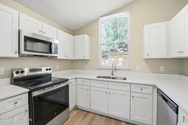a kitchen with cabinets appliances a sink and a window