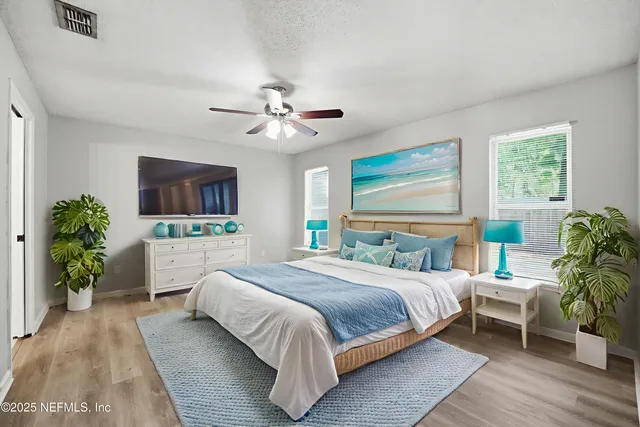 a bedroom with a large bed a chandelier and windows