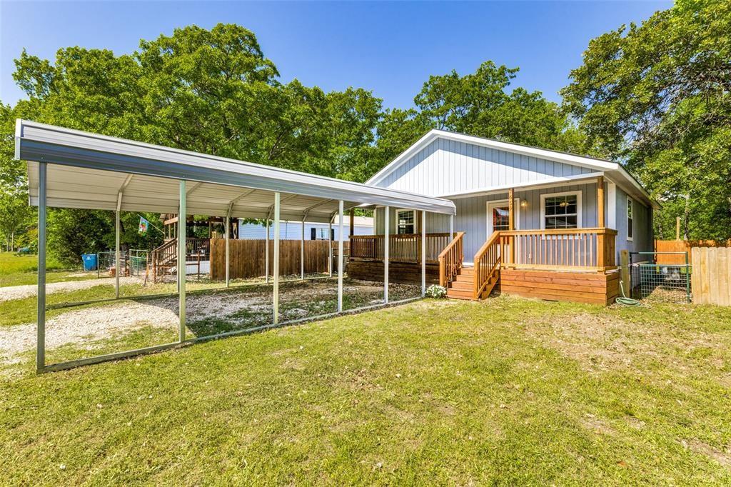 View of front of home featuring a carport, covered porch, and a front lawn