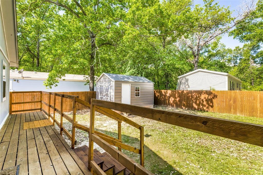 7659 Double Bridge Road Mabank, TX 75156 - Photo 21 of 22 Deck featuring a storage shed, a fenced backyard, and view of wooded area