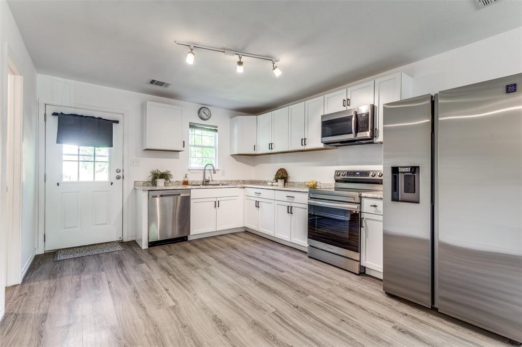 7659 Double Bridge Road Mabank, TX 75156 - Photo 5 of 22 Kitchen with appliances with stainless steel finishes, white cabinets, light wood-style floors, and rail lighting