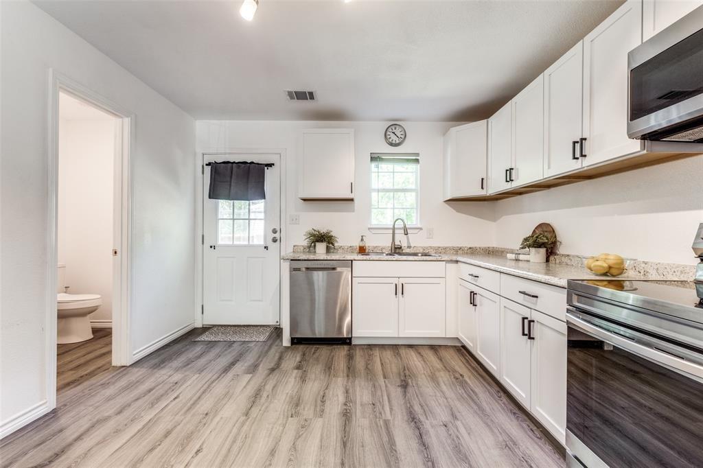 7659 Double Bridge Road Mabank, TX 75156 - Photo 7 of 22 Kitchen featuring stainless steel appliances, light wood-style flooring, white cabinetry, and light stone counters
