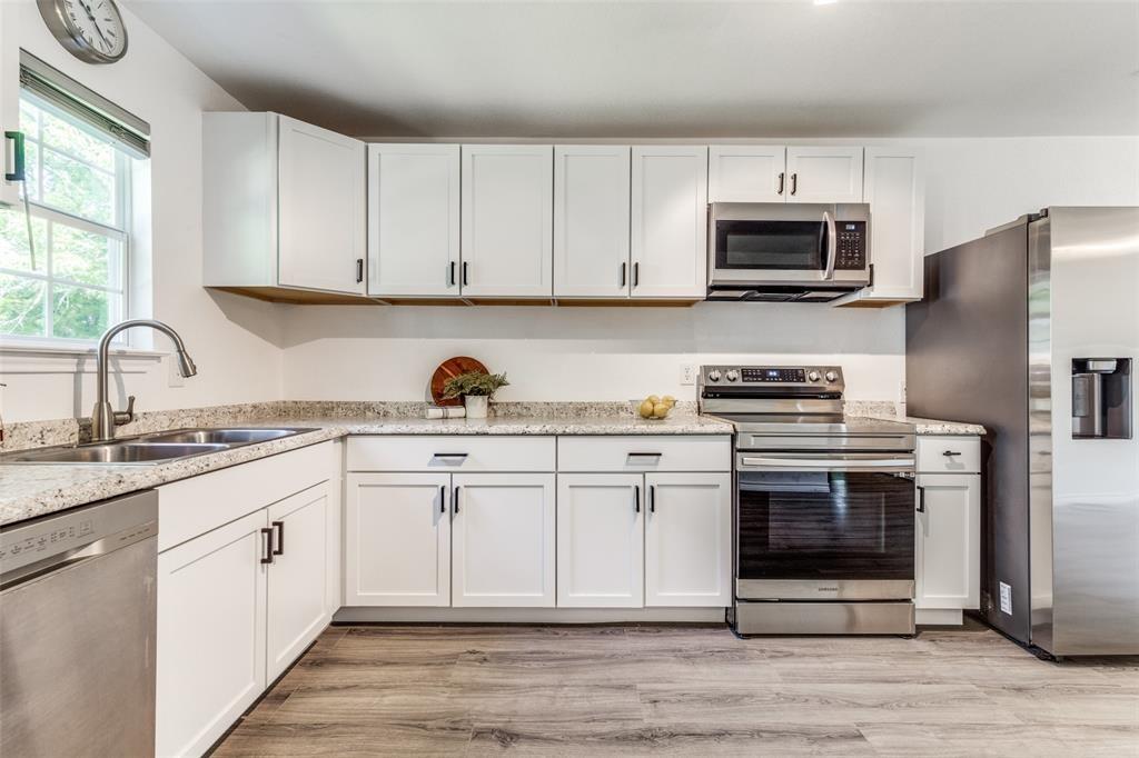 7659 Double Bridge Road Mabank, TX 75156 - Photo 8 of 22 Kitchen with stainless steel appliances, light wood finished floors, and white cabinetry