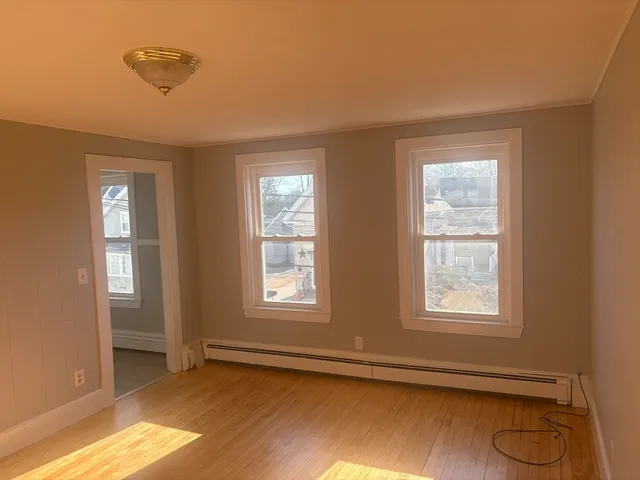 a view of an empty room with a window and wooden floor