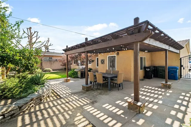 a view of a patio with table and chairs near a barbeque