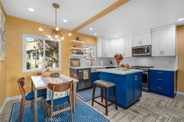 a kitchen with stainless steel appliances granite countertop a stove a sink dishwasher a dining table and chairs with wooden floor