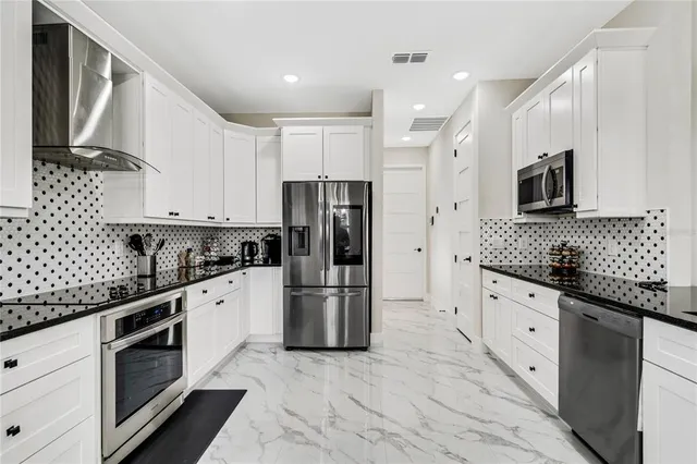 a large kitchen with stainless steel appliances a refrigerator sink and cabinets