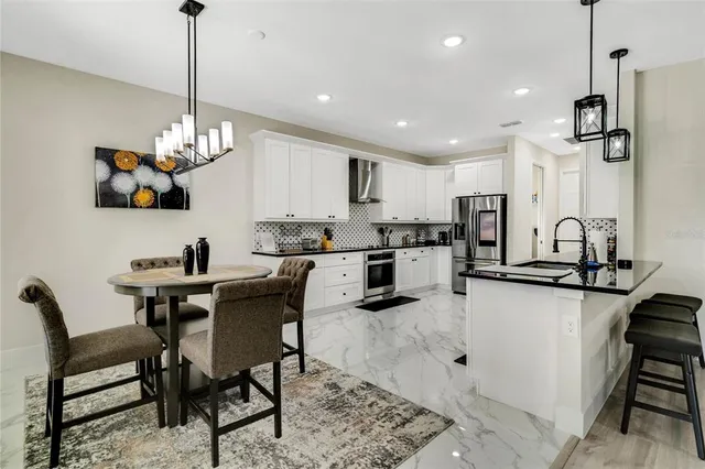 a kitchen with stainless steel appliances kitchen island granite countertop a table chairs and a refrigerator