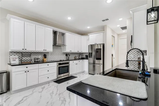 a kitchen with stainless steel appliances granite countertop a sink refrigerator and cabinets