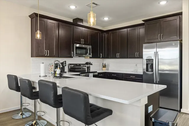 a kitchen with granite countertop a refrigerator a stove a sink and chairs