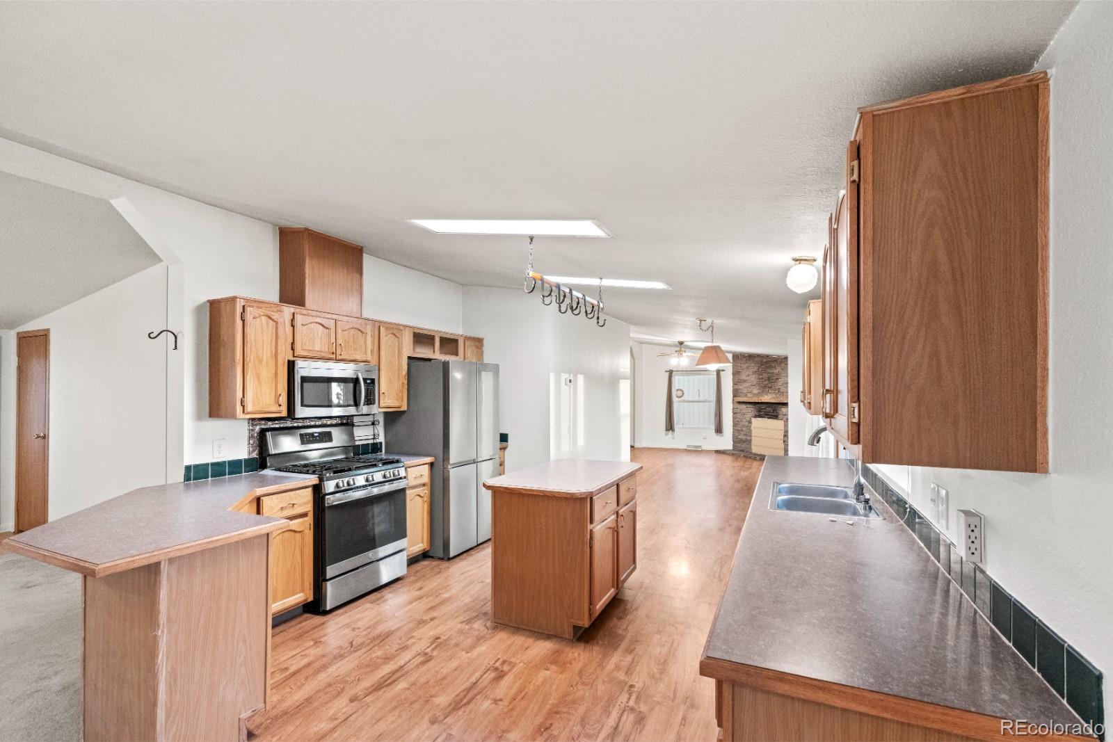 21105 McDaniels Road Calhan, CO 80808 - Photo 3 of 32 a kitchen with stainless steel appliances a stove a sink a refrigerator white cabinets and wooden floor