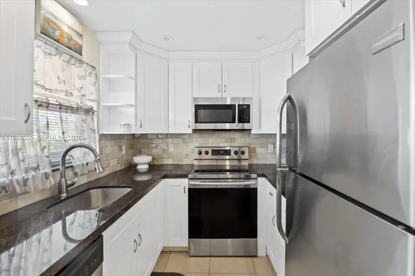 a kitchen with stainless steel appliances a refrigerator sink and white cabinets