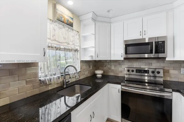 a kitchen with granite countertop a sink a stove and microwave