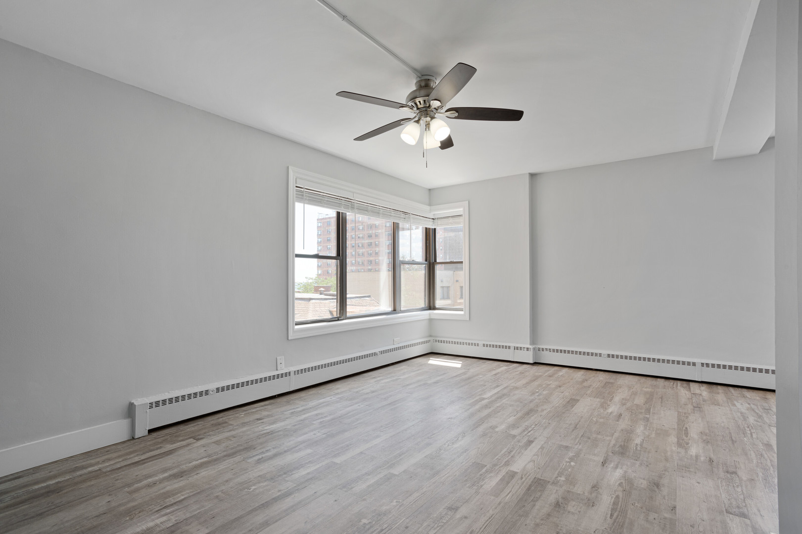 5858 North Sheridan Road, Unit 508 Chicago, IL 60660 - Photo 6 of 17 an empty room with wooden floor fan and windows
