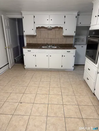 a kitchen with granite countertop a stove a sink and a refrigerator