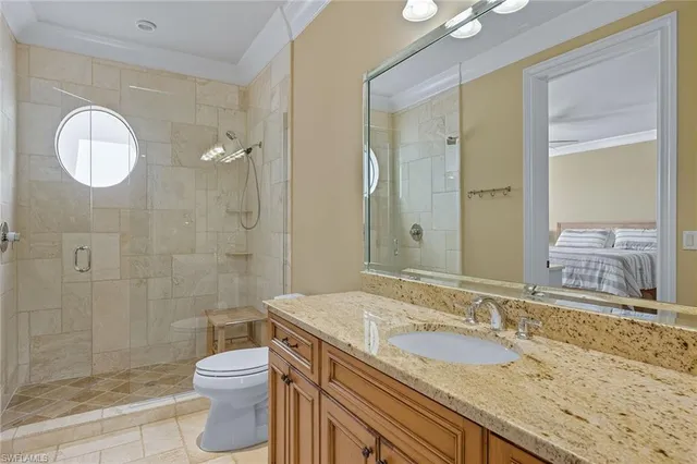 a bathroom with a granite countertop sink a toilet a mirror and shower
