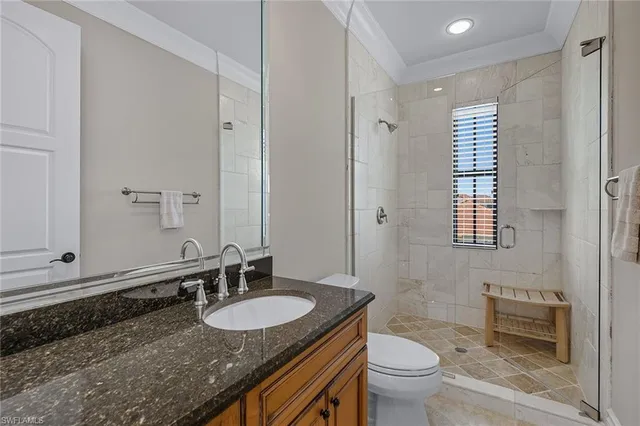 a bathroom with a granite countertop sink a toilet a mirror and shower