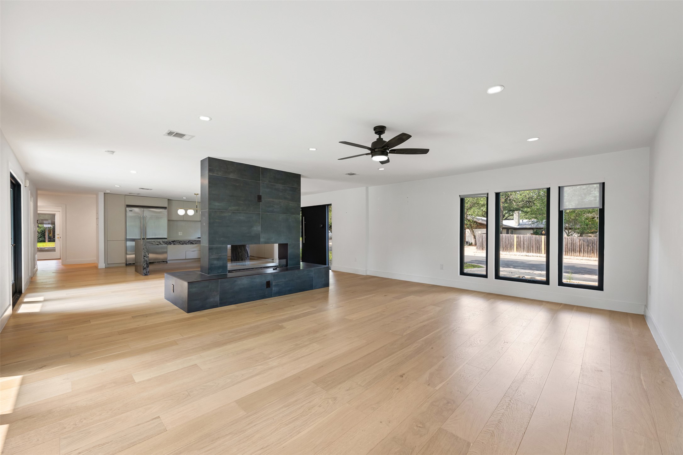 8900 Point W Drive Austin, TX 78759 - Photo 8 of 40 Blonde hardwood floors extend through this open-concept living space with a dramatic fireplace centerpiece.