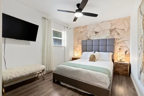 a bedroom with a bed and a flat tv screen on dresser