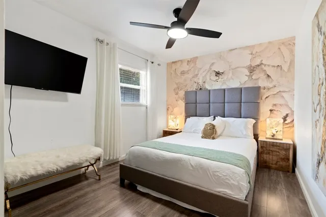 a bedroom with a bed and a flat tv screen on dresser