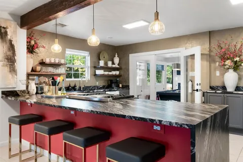 a kitchen with kitchen island granite countertop a table chairs stove and wooden cabinets