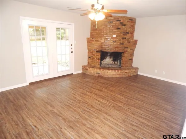 an empty room with wooden floor fireplace and windows