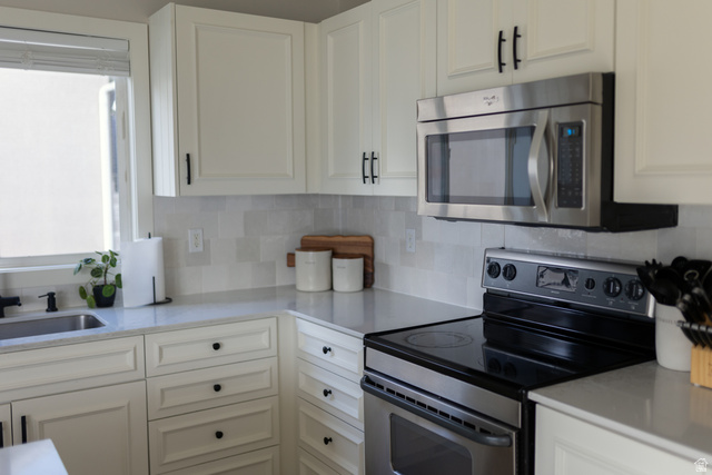 1204 North 3020th Street West Provo, UT 84601 - Photo 14 of 35 Kitchen featuring white shaker-style cabinetry with matte black hardware, stainless steel appliances including a microwave and electric range, light-toned countertops