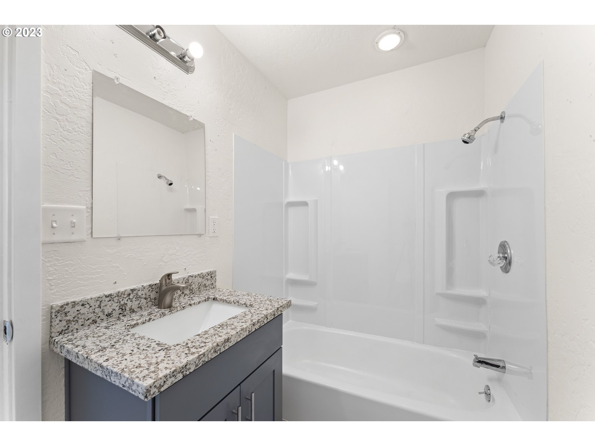 835 L Street Springfield, OR 97477 - Photo 30 of 40 a bathroom with a granite countertop sink a mirror and a bathtub