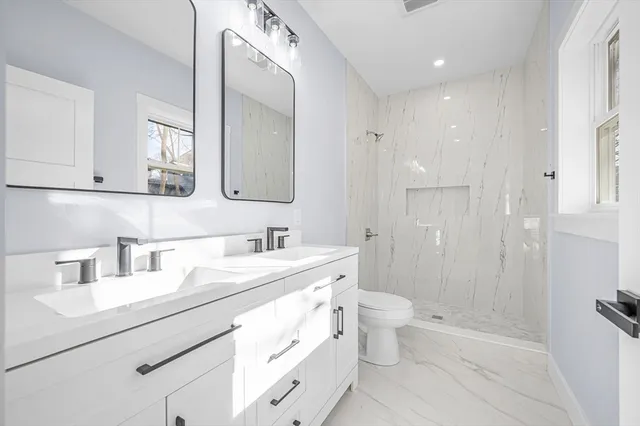 a bathroom with a sink a toilet a shower and a mirror