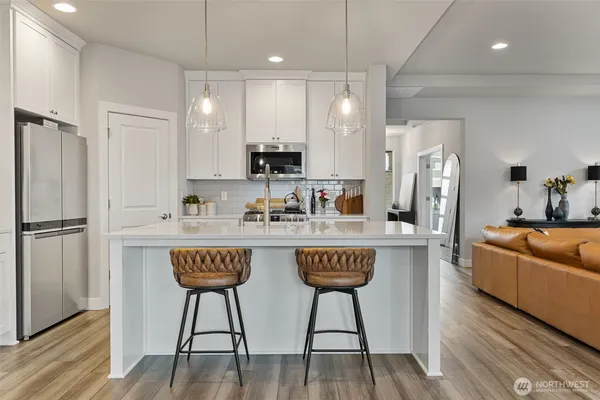a kitchen with stainless steel appliances granite countertop a sink a refrigerator and a stove top oven with wooden floor