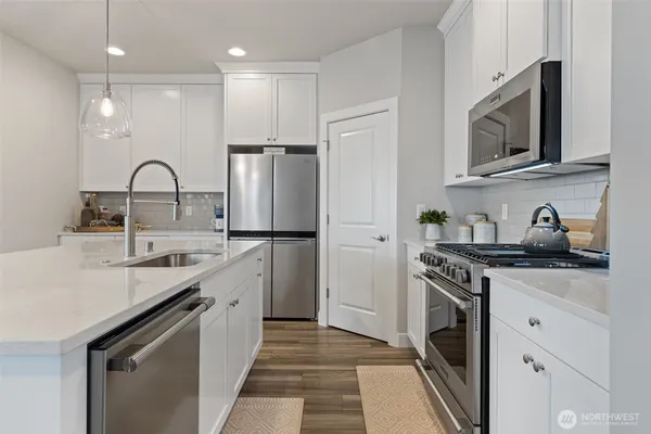 a kitchen with a sink stainless steel appliances and white cabinets