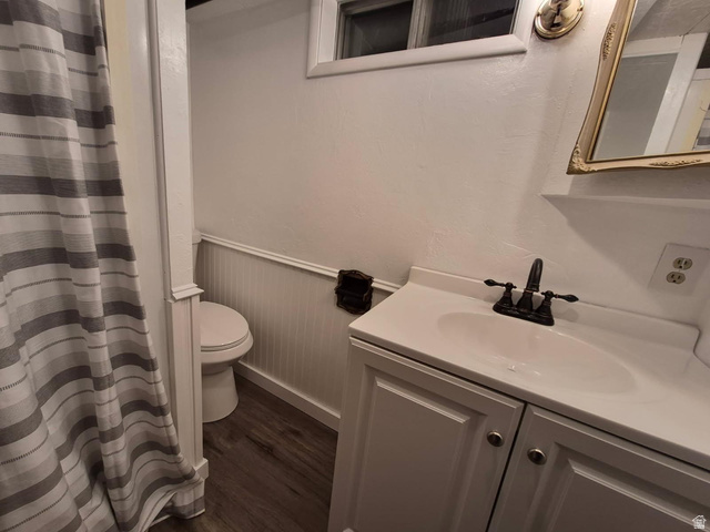 722 Adams Street Montpelier, ID 83254 - Photo 12 of 22 Bathroom featuring curtained shower, vanity, dark wood-style floors, and a wainscoted wall