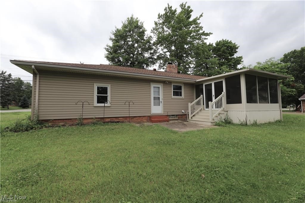 890 Wadsworth Road Medina, OH 44256 - Photo 15 of 22 Back of property with a sunroom, entry steps, a lawn, and a chimney