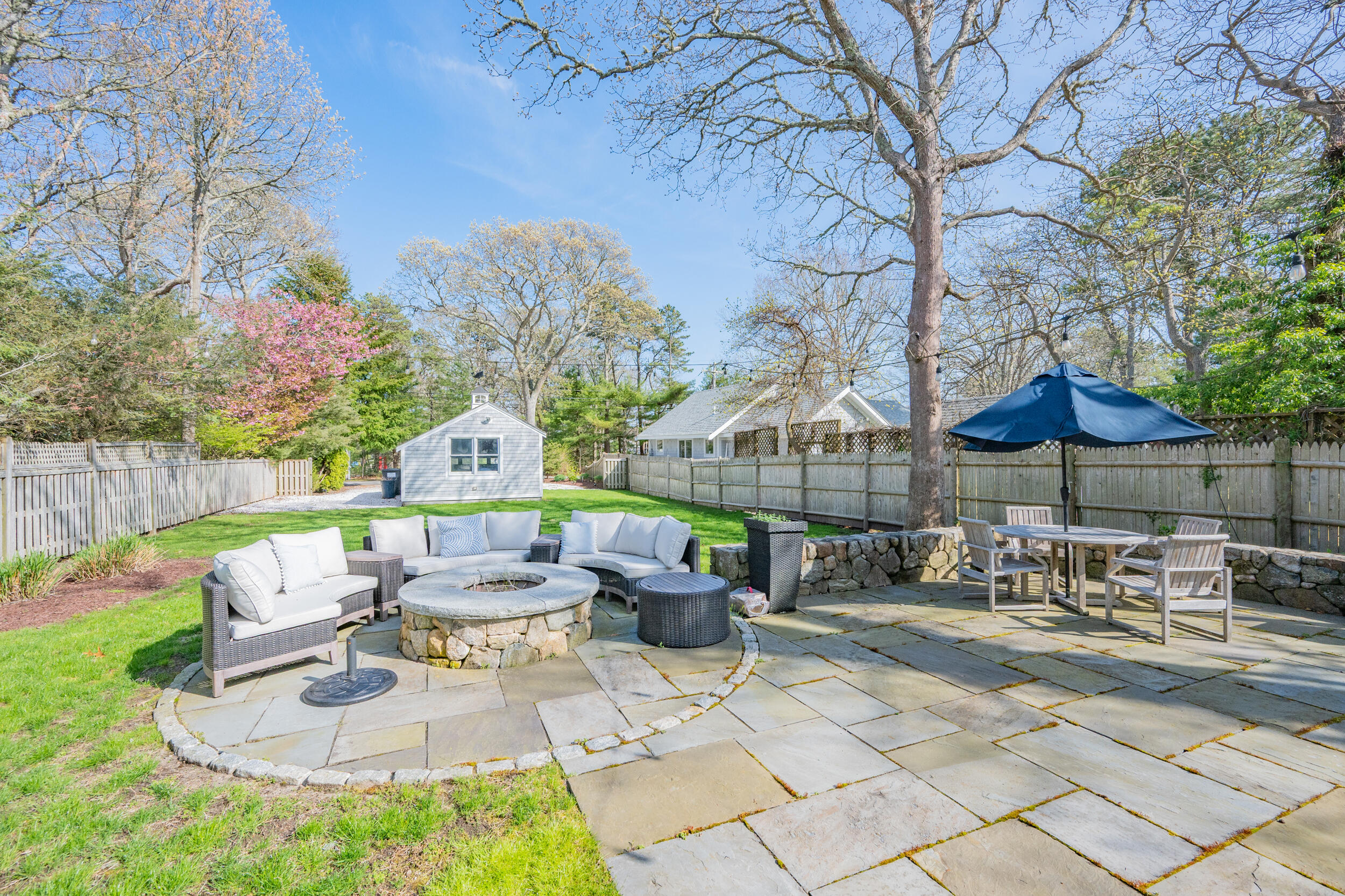 21 Bayview Road Mashpee, MA 02649 - Photo 66 of 85 a view of a patio with table and chairs under an umbrella with large trees