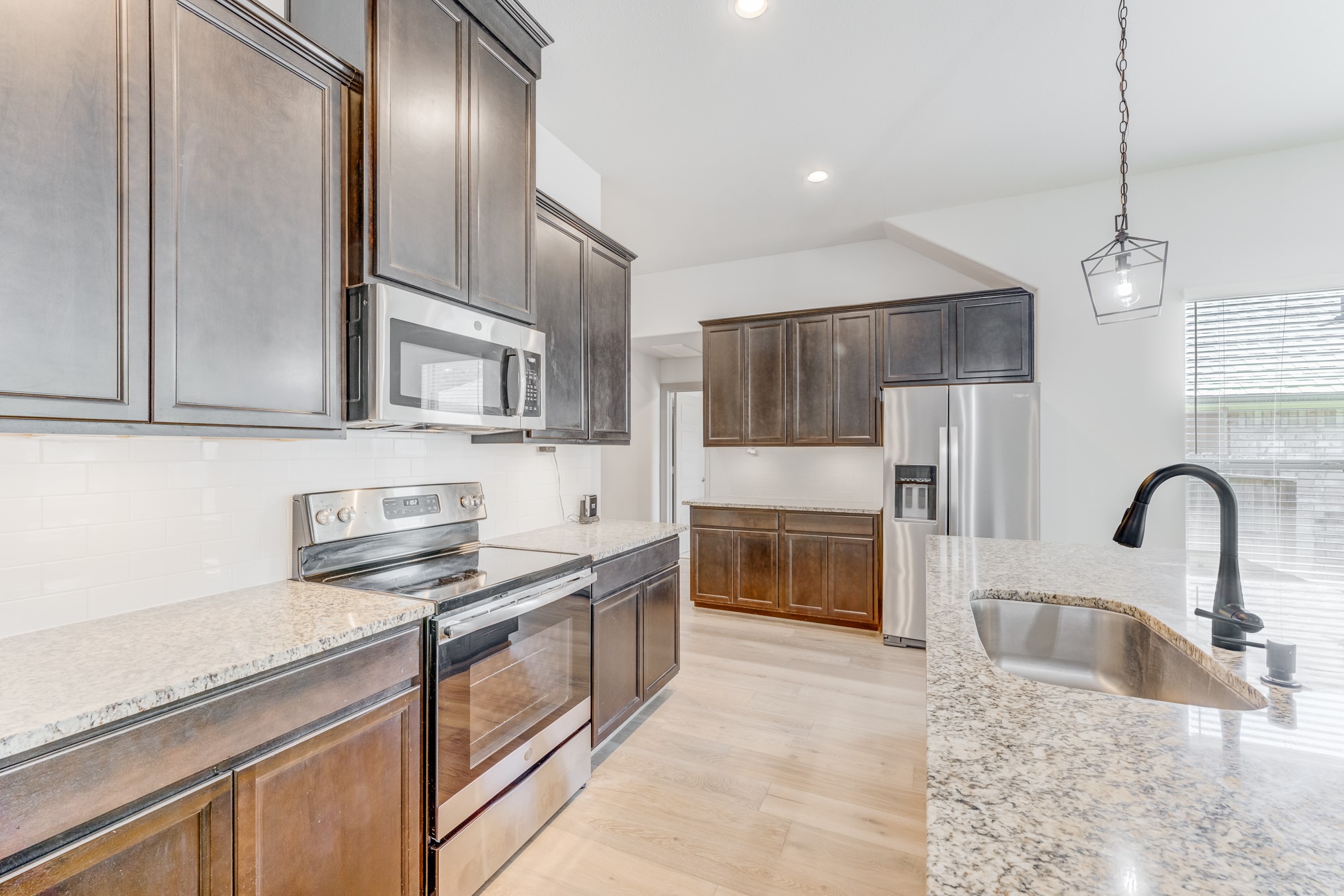 11913 Mockingbird Lane Montgomery, TX 77356 - Photo 2 of 19 a kitchen with granite countertop a stove a sink and a refrigerator