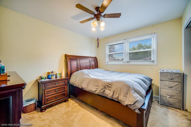 a bedroom with a bed dresser and a chandelier