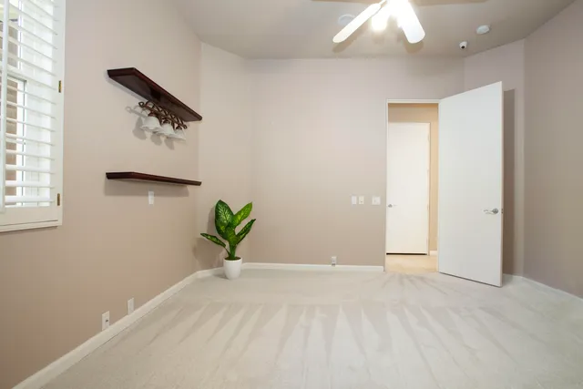 an empty room with windows and fan